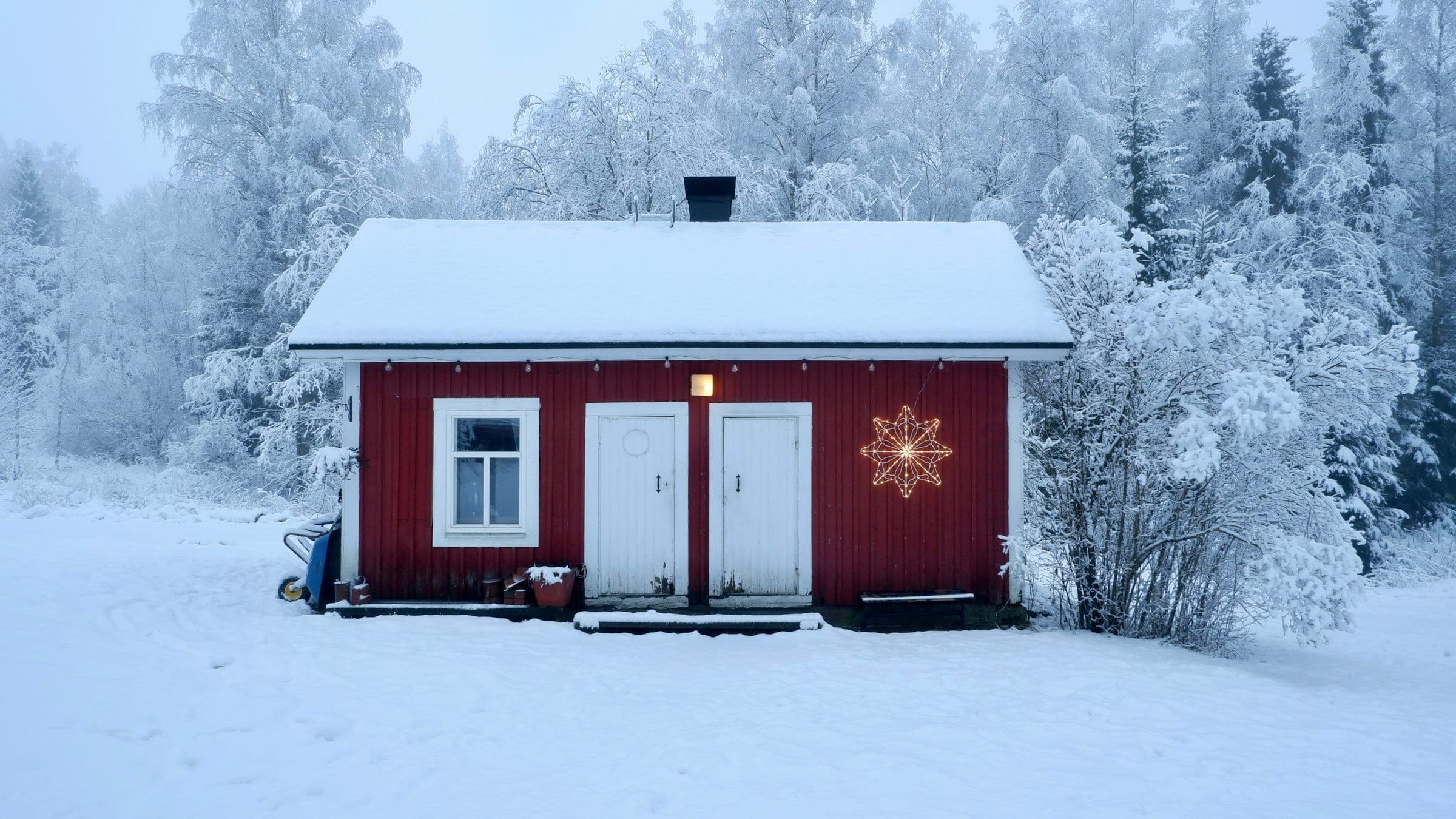 A red wooden cabin in a frozen forest, a lit star hanging by the door